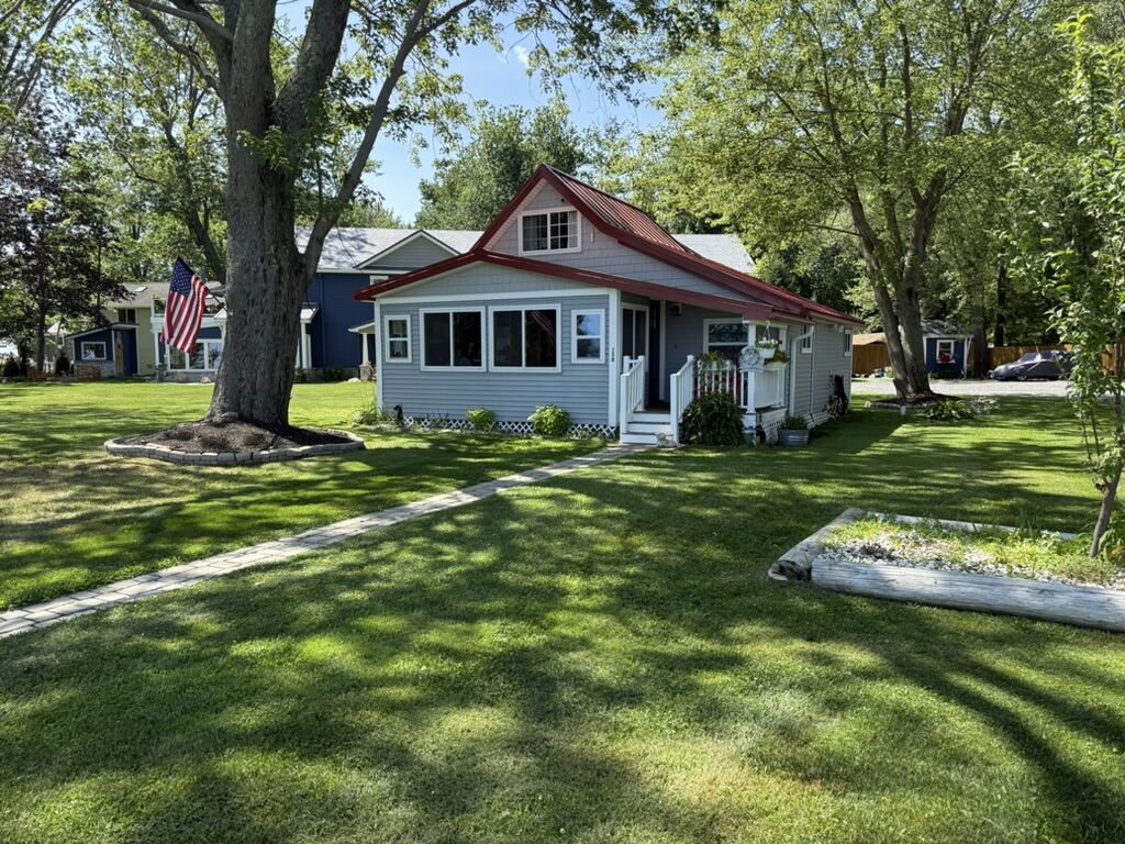 Constantia NY Guest Cottage – gray cottage with red roof and American flag